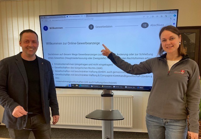 Bürgermeister Holger Siemon und Verena Schneider vom Bürgerbüro zeigen den neuen Online-Vorgang am großen Fernsehbildschirm
