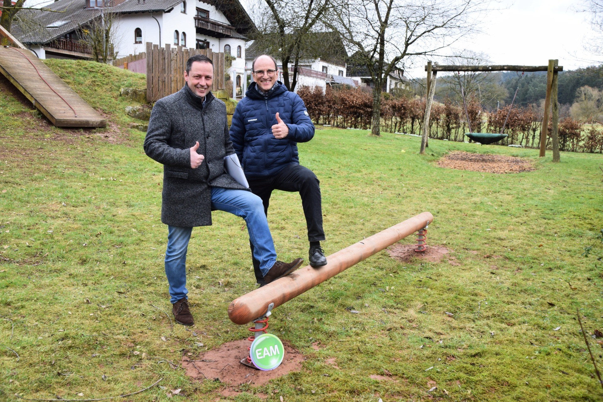 Bürgermeister Holger Siemon und Marcus Hief / EAM bei der Übergabe des Wackelbalkens auf dem Spielplatz „Rodenbachweg“ im Ortsteil Simtshausen
